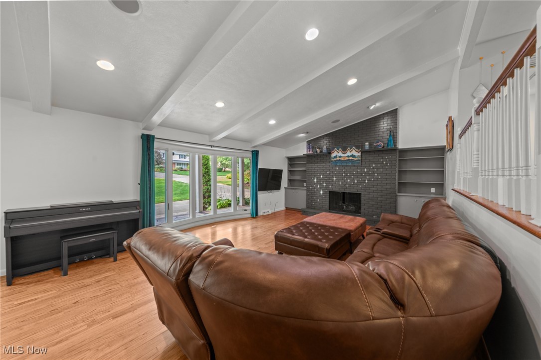 Living room with a brown leather sectional, brick fireplace, built-in shelves, and sliding glass doors.
