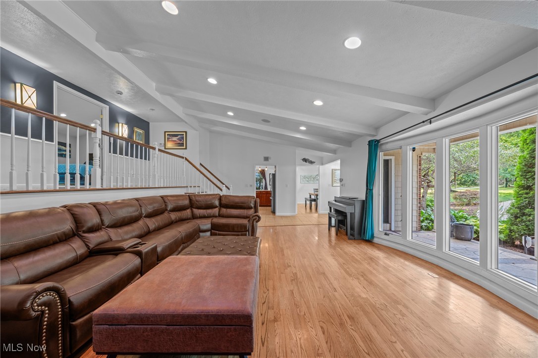 Living room with a brown leather sectional, raised loft railing, and glass doors overlooking the garden.