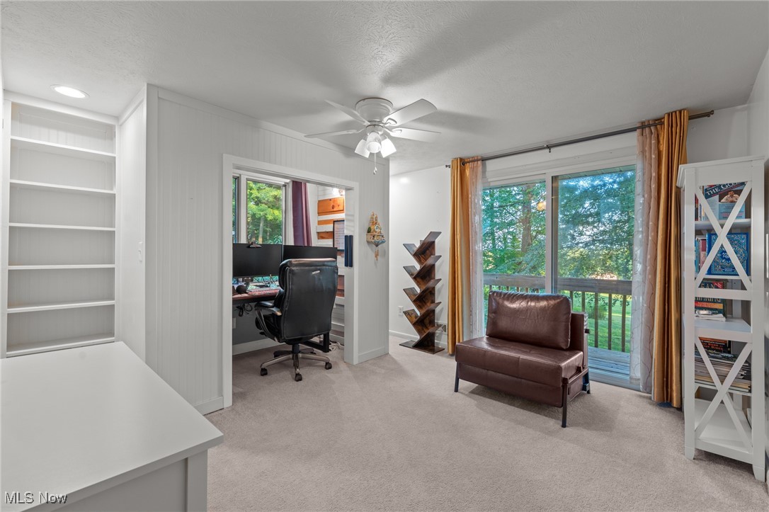 Home office with built-in shelving, a computer nook, and sliding doors to a wooded balcony.