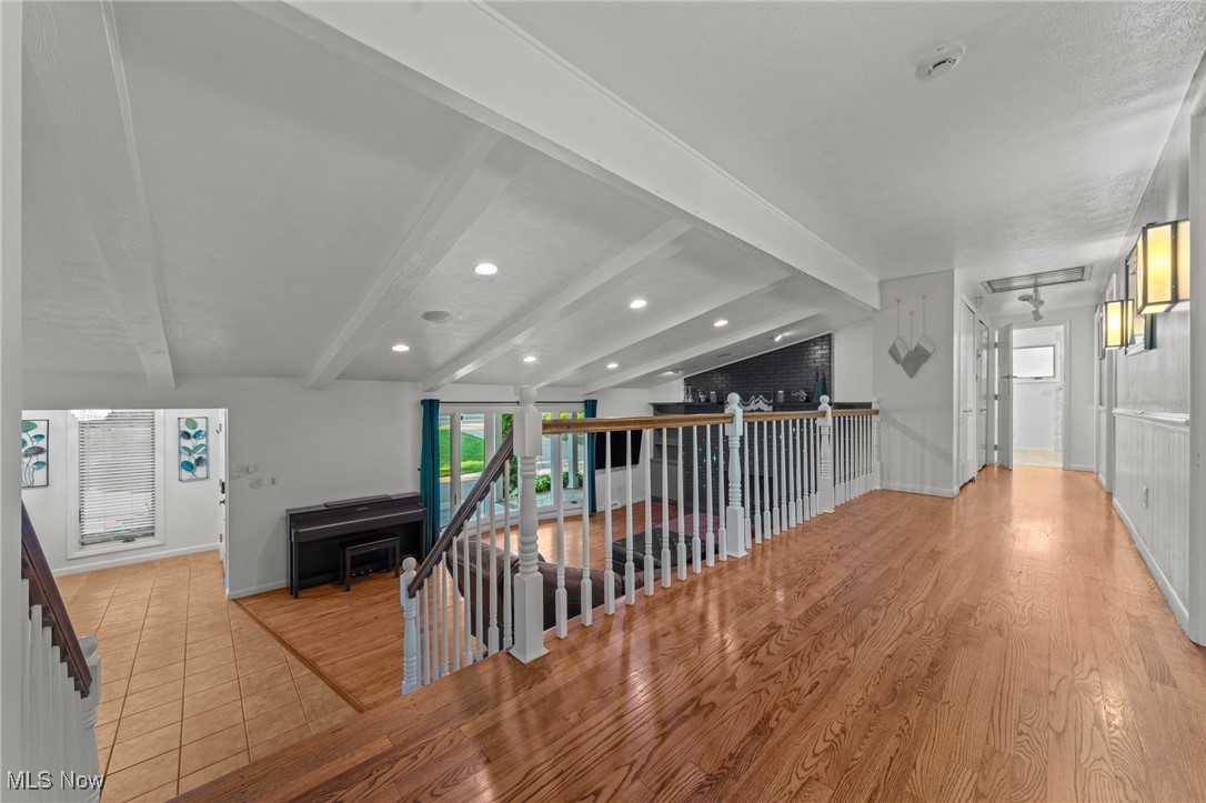 Upper-level landing with hardwood floors and white railing overlooking a lower-level sitting area.