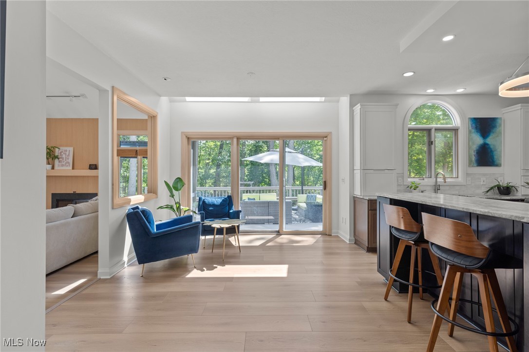 Open kitchen and living area with blue lounge chairs, wood flooring, and doors to deck.