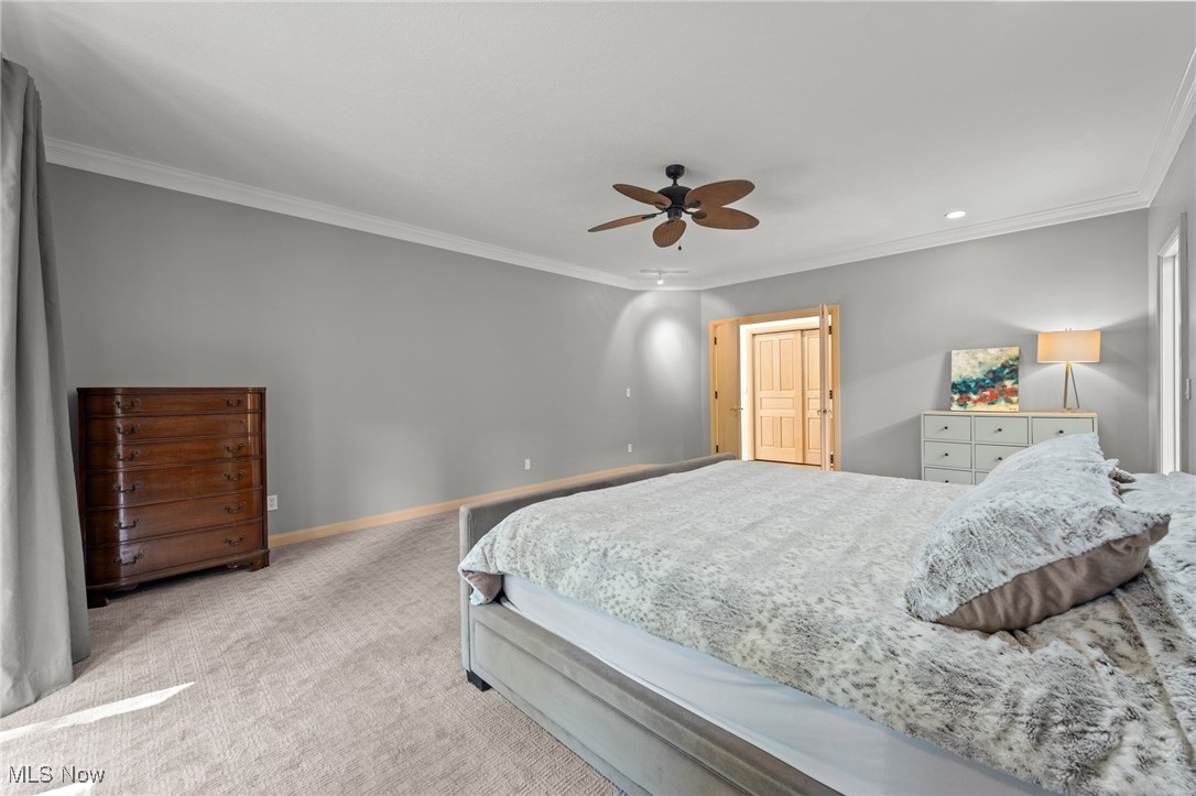Bedroom with a large pale bed, gray walls, carpet, and a ceiling fan.