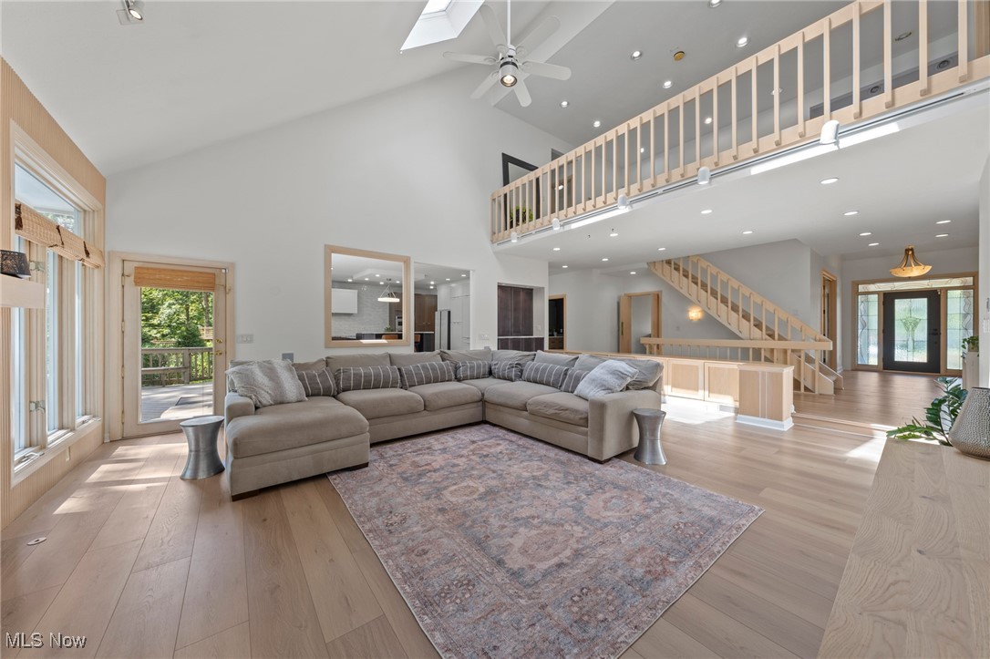 Two-story great room with a large sectional, vaulted ceiling, loft railing, and hardwood floors.