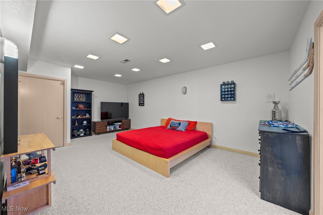 Furnished bedroom with a low wooden bed, bright red bedding, and sports memorabilia.