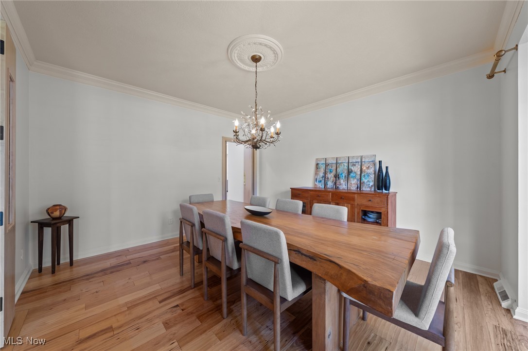 Dining room with a live-edge wood table, gray chairs, hardwood floors, and a chandelier.