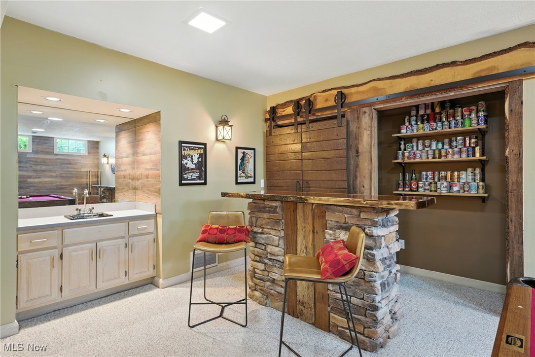Basement recreation room with a stone-and-wood bar, stocked shelves, and a barn-style sliding door.