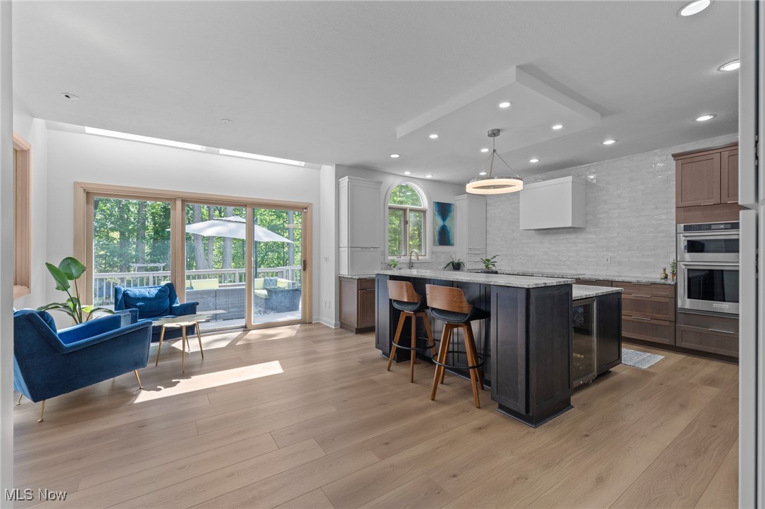 Open kitchen and living area with a dark island, blue seating, and wooded deck view.