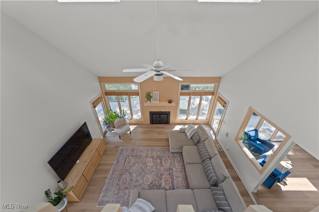 Living room with a vaulted ceiling, fireplace, large windows, and sectional sofa.