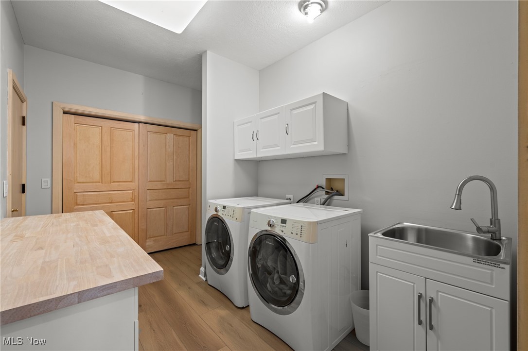 Laundry room with front-loading washer and dryer, utility sink, and butcher-block countertop.