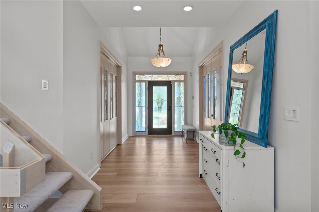 Entry foyer with a glass-paneled front door, carpeted staircase, and blue-framed mirror above a console.