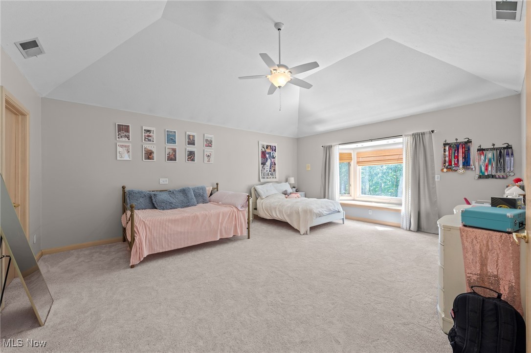 Spacious bedroom with vaulted ceiling, two beds, and a wide window overlooking trees.