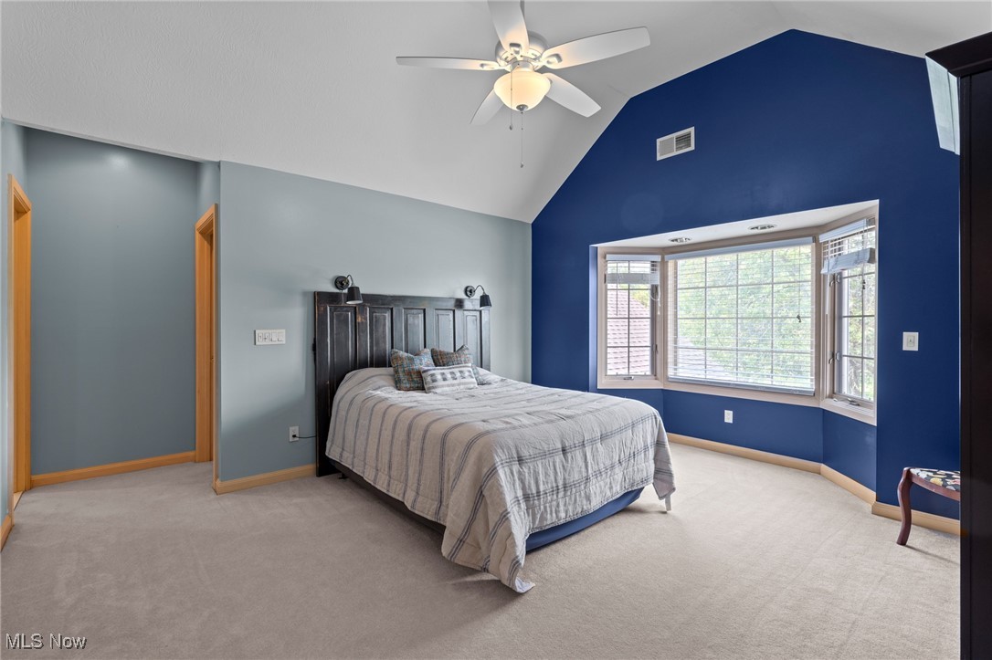 Bedroom with a dark wood headboard, deep blue accent wall, and large bay window.
