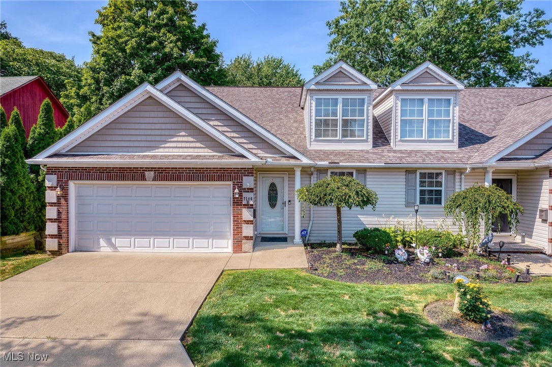 Two-story home with a brick double garage, roof dormers, and landscaped front yard.