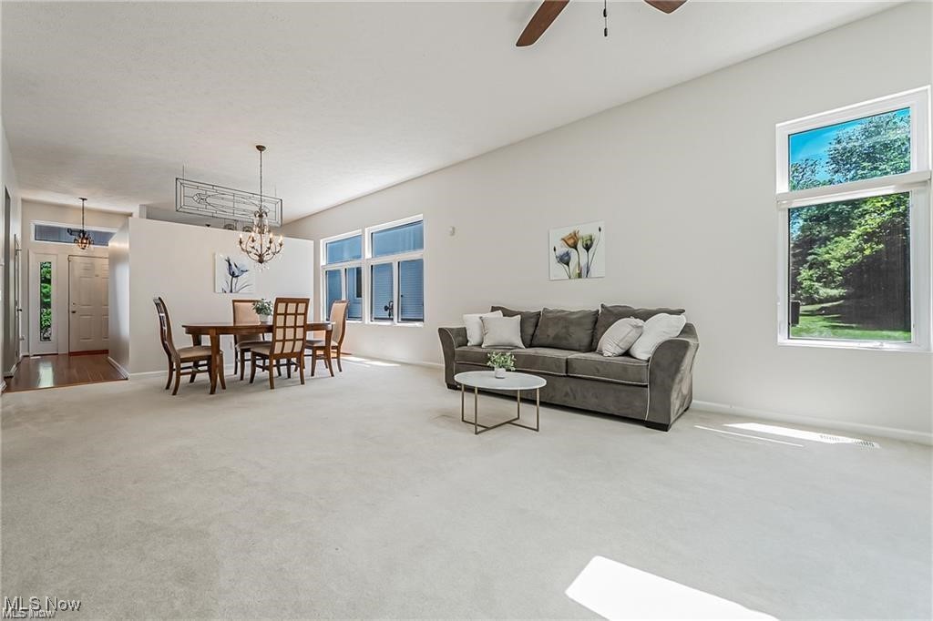 Open living and dining room with a gray sofa, dining set, and large windows.