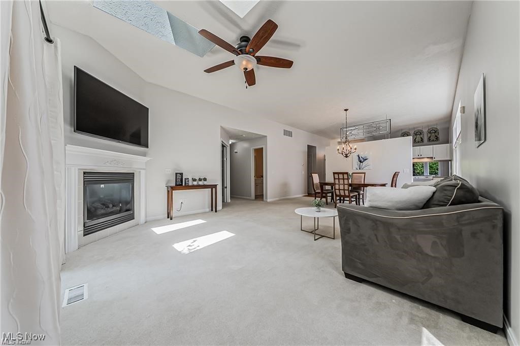 Furnished living room with a white fireplace, gray sofa, and dining area.