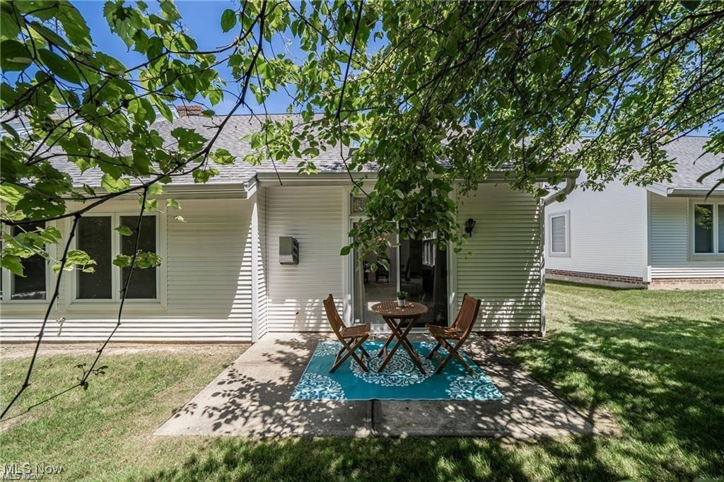 Home’s shaded rear patio with a table, chairs, and blue patterned rug.