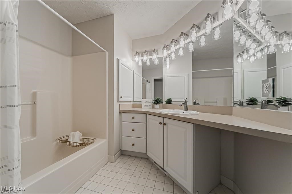 Bathroom with a white tub, long vanity, wall-to-wall mirrors, and globe vanity lights.