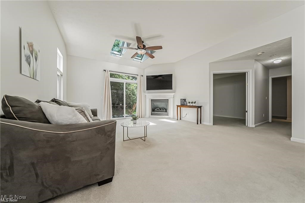 Living room with a sectional sofa, skylights, fireplace, and sliding glass doors to greenery.