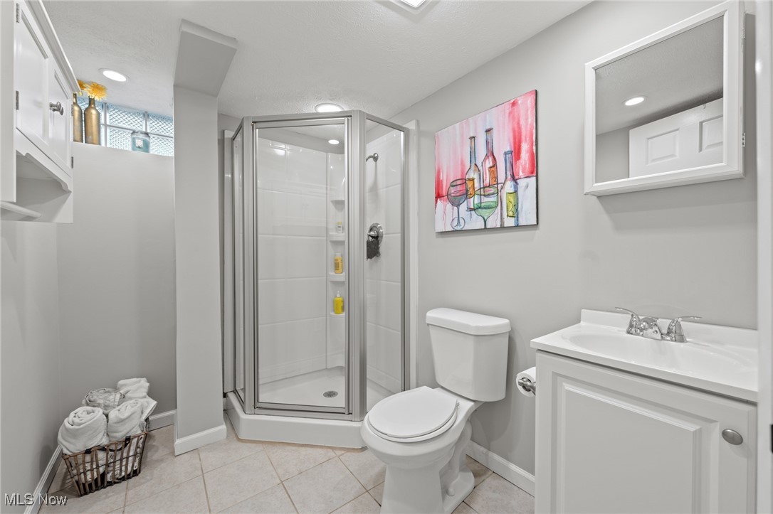 Bathroom with glass corner shower, white vanity, gray walls, and colorful wine-themed artwork.