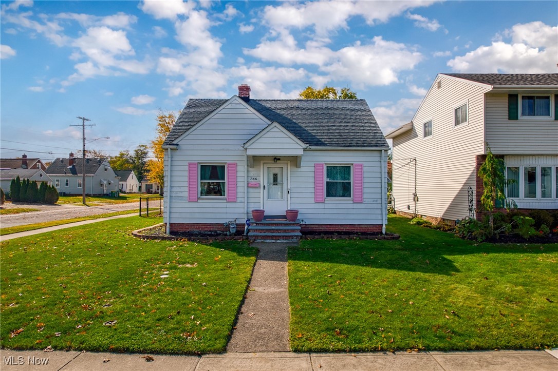 White house with pink shutters and a walkway leading to its front door.