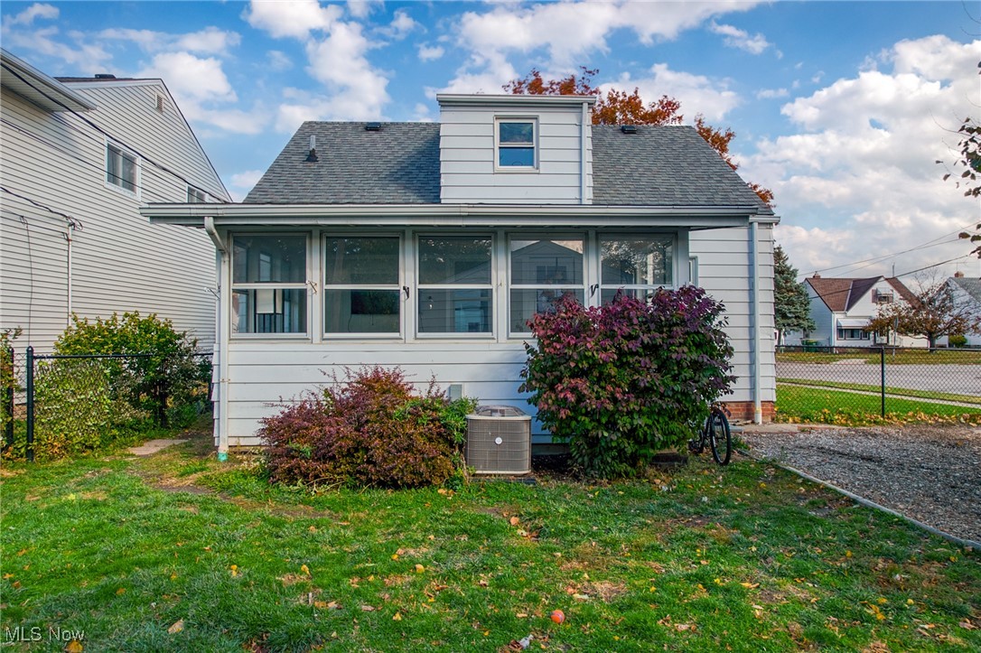 Rear of a white-sided home with an enclosed porch, upper dormer, and fenced yard.