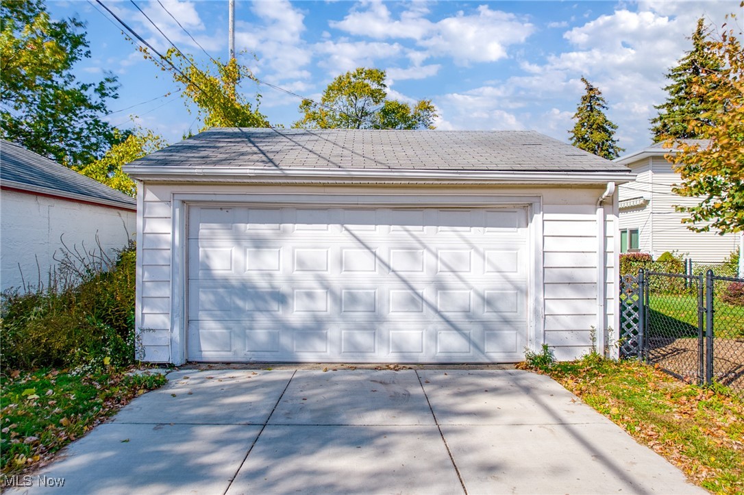 Detached white garage with a wide paneled door and concrete driveway.