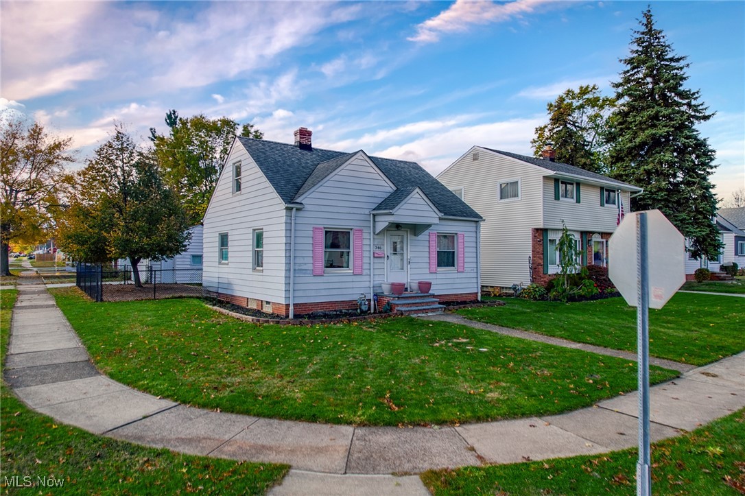 White-sided corner house with pink shutters and a small covered entry.