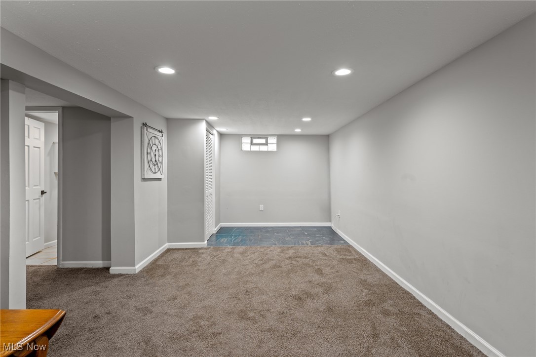 Unfurnished carpeted room with a tiled area, high window, and recessed lights.