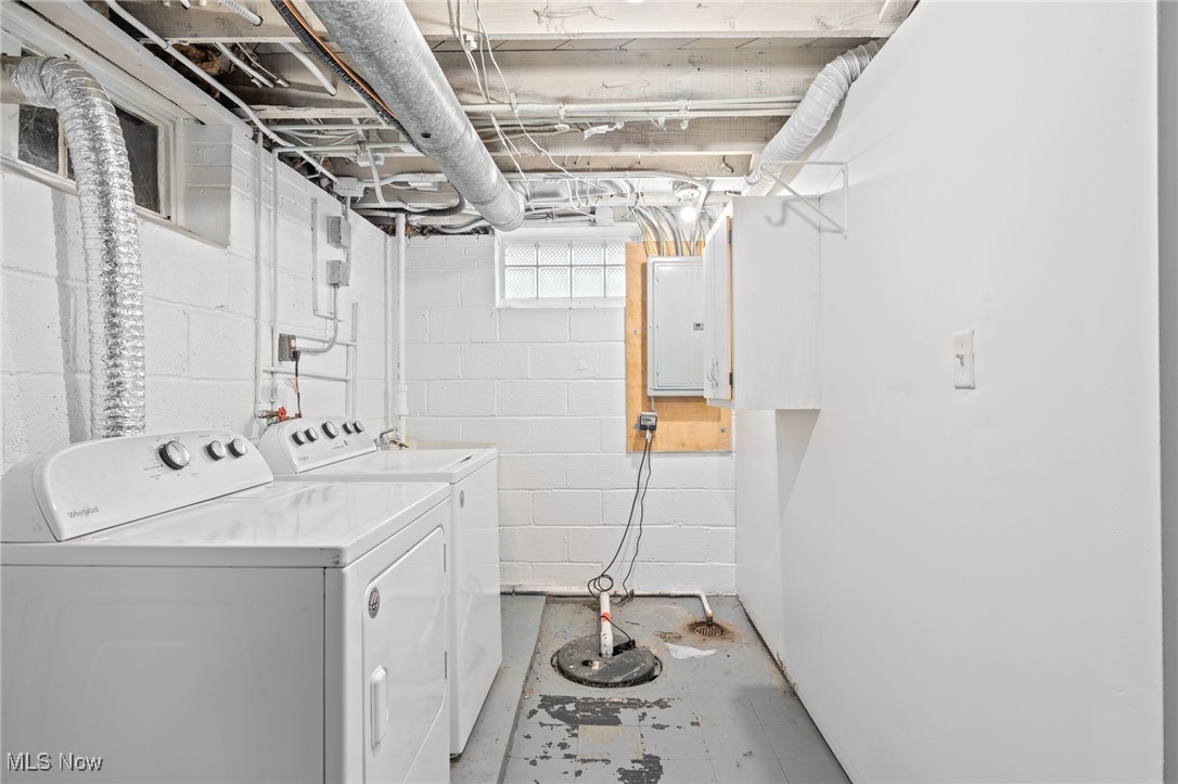 Basement laundry room with a white washer and dryer beneath exposed ductwork.