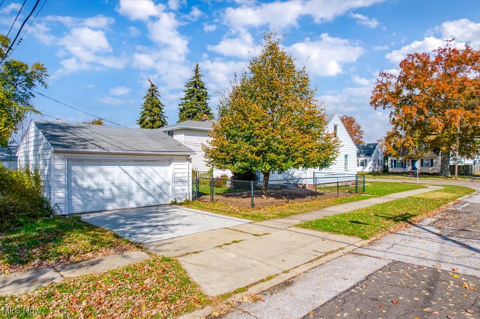 Home with a detached white garage and large autumn tree in the front yard.