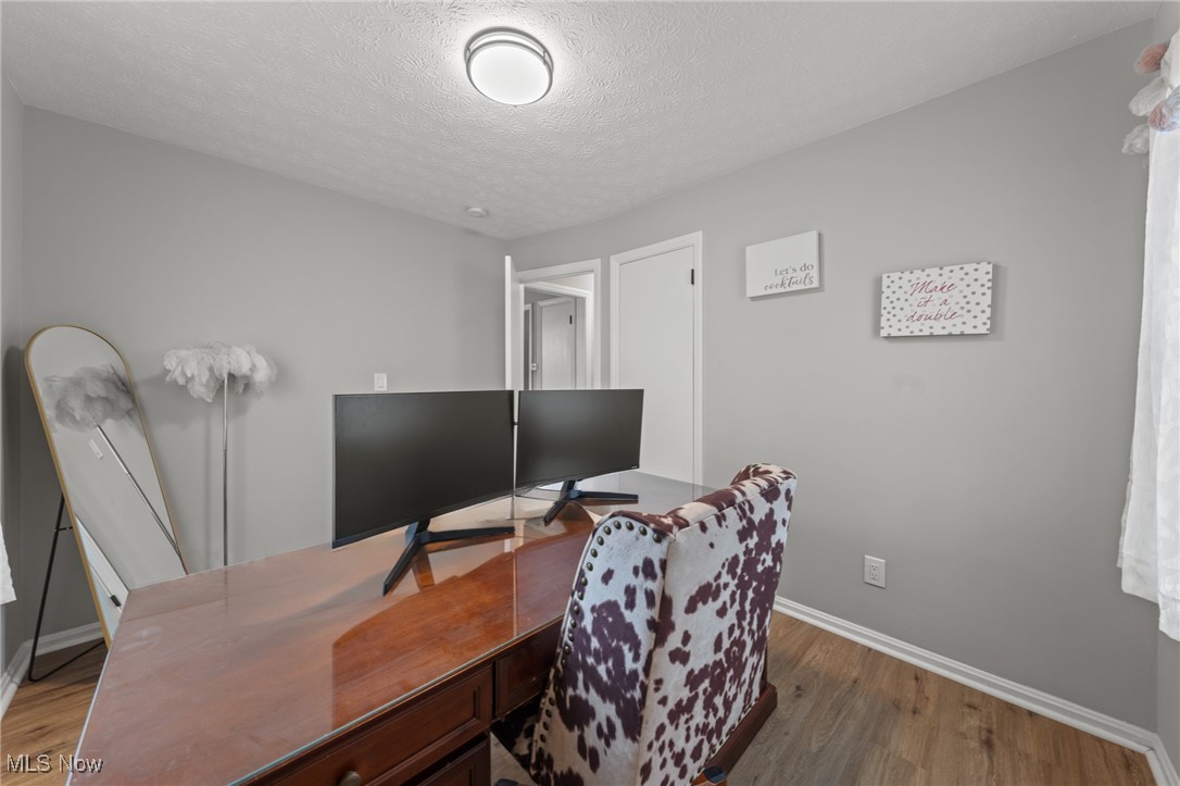 Home office with a polished desk, dual monitors, and a patterned chair.