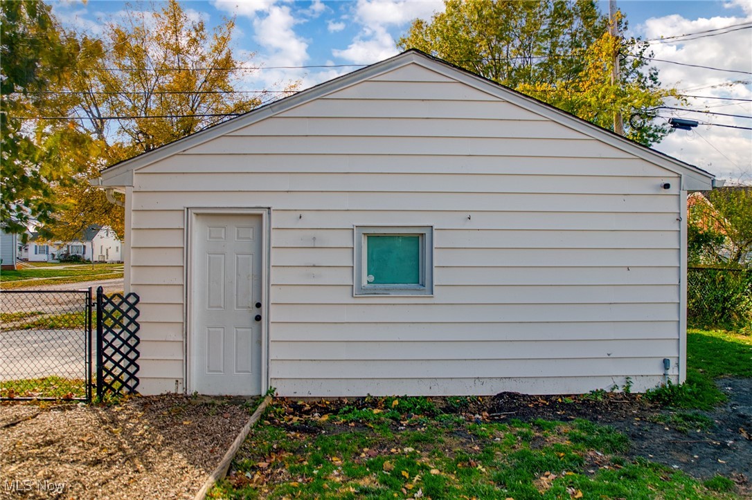 White detached garage with a gabled roof, side door, and small window.