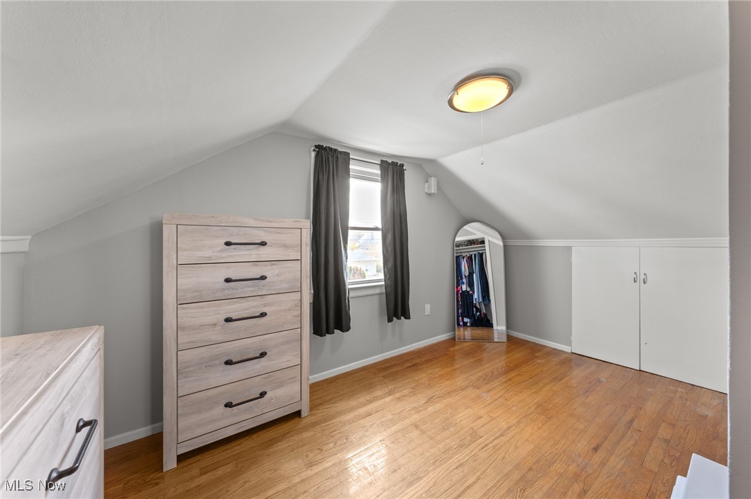 Finished attic bedroom with sloped ceilings, hardwood floors, and built-in storage cabinets.