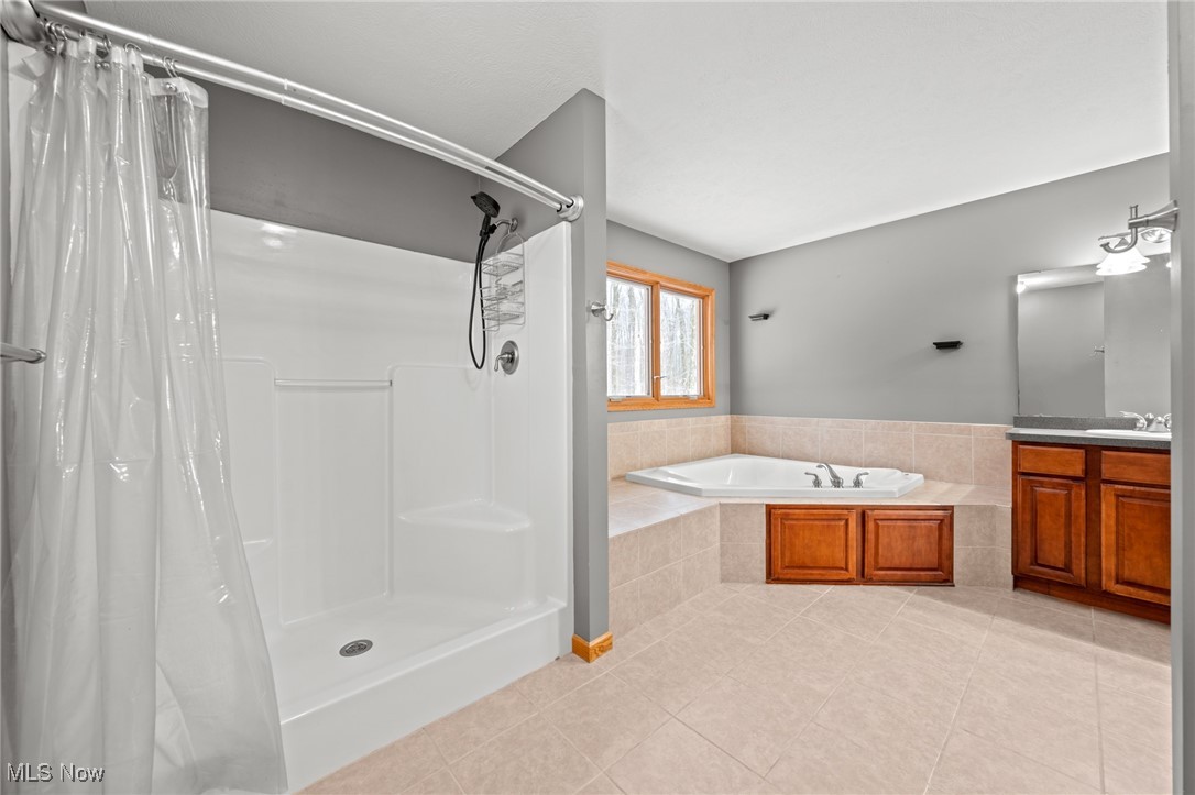 Bathroom with a corner soaking tub, wood vanity, and separate shower stall.