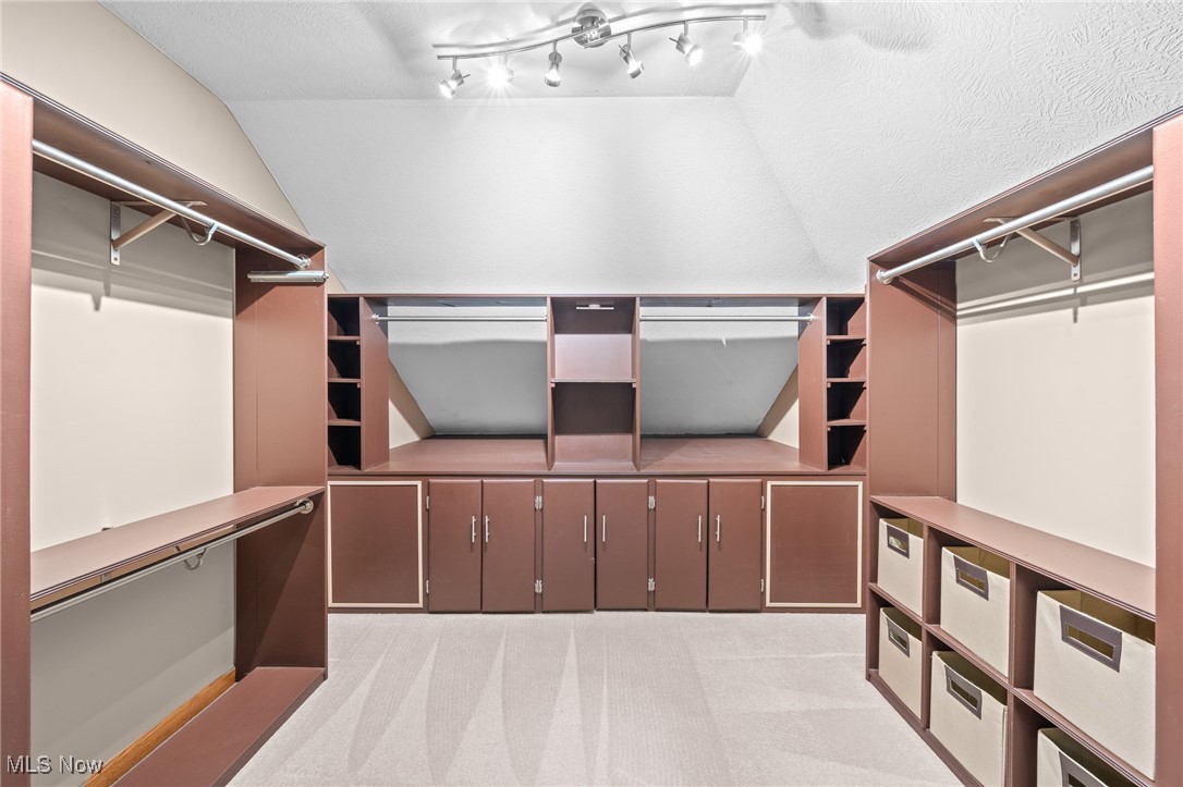 Walk-in closet with extensive built-in cabinetry, hanging rods, shelves, and fabric storage bins.