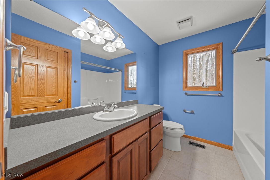 Bathroom with blue walls, a long wooden vanity, a large mirror, and a bathtub.