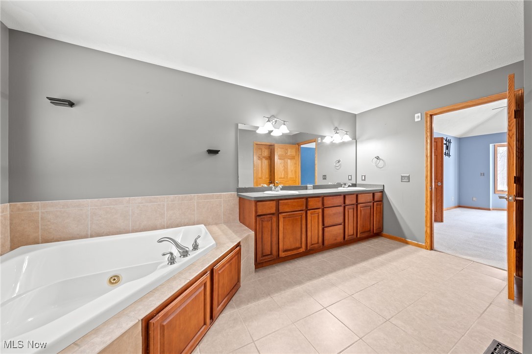 Bathroom with a built-in soaking tub and long double vanity with wood cabinets.
