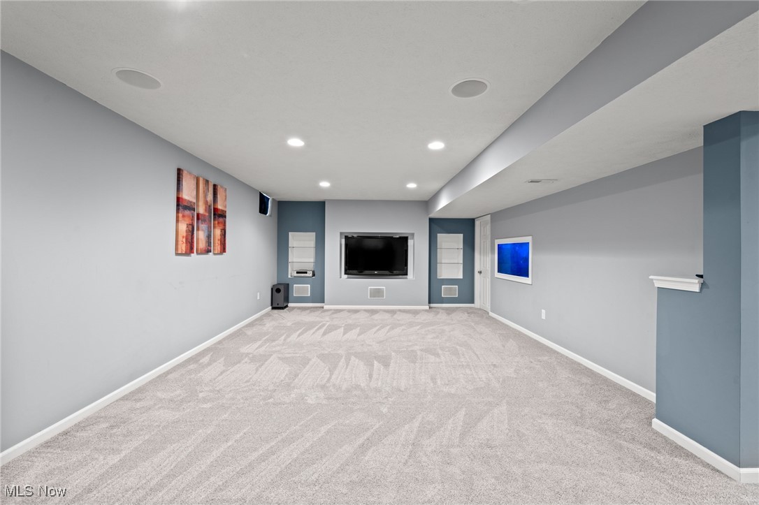 Spacious carpeted family room with recessed lighting and a built-in television alcove.