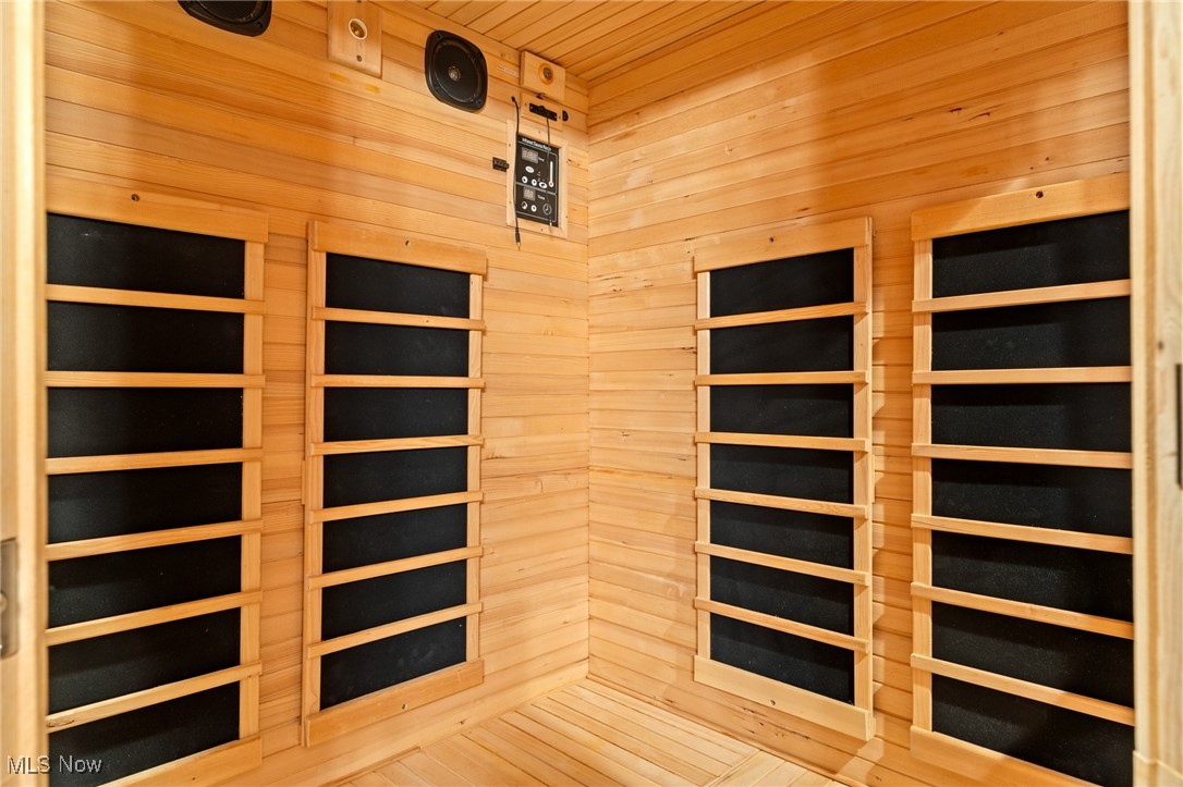 Wood-paneled sauna with black heating panels, a wall control panel, and ceiling speakers.