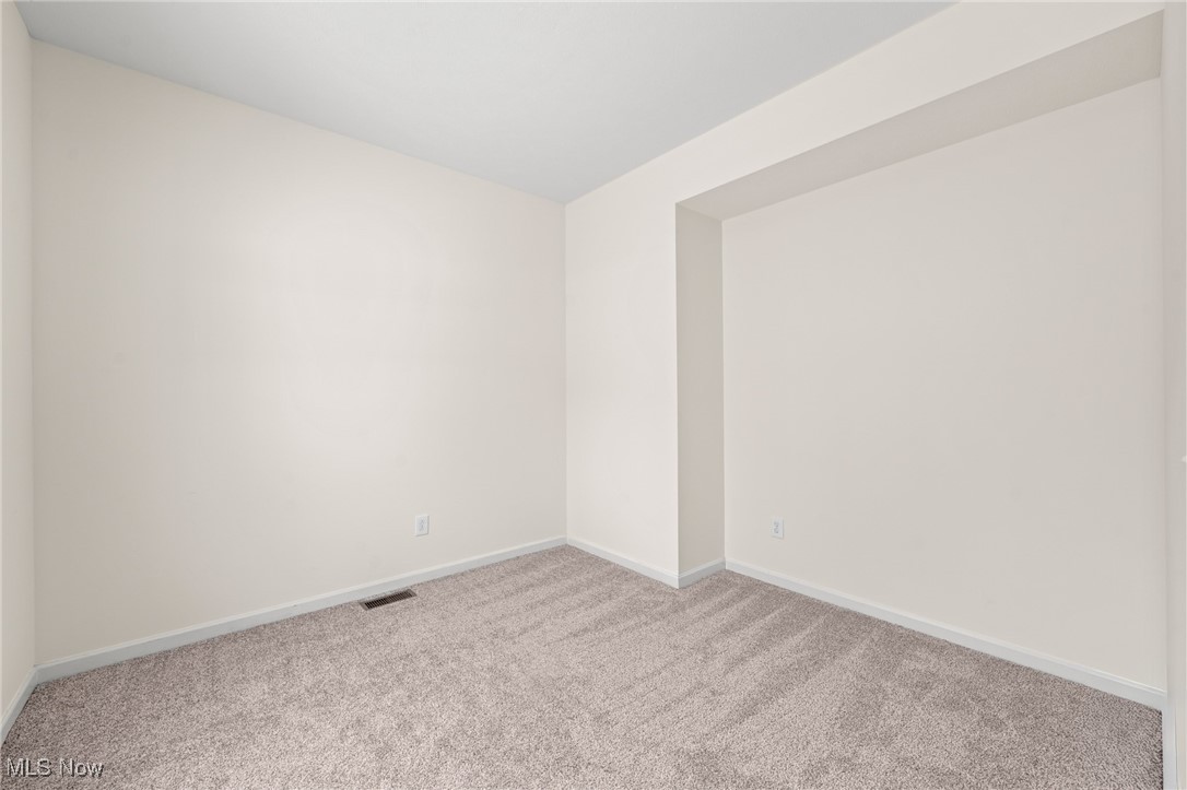Empty carpeted room with neutral walls and a recessed section.