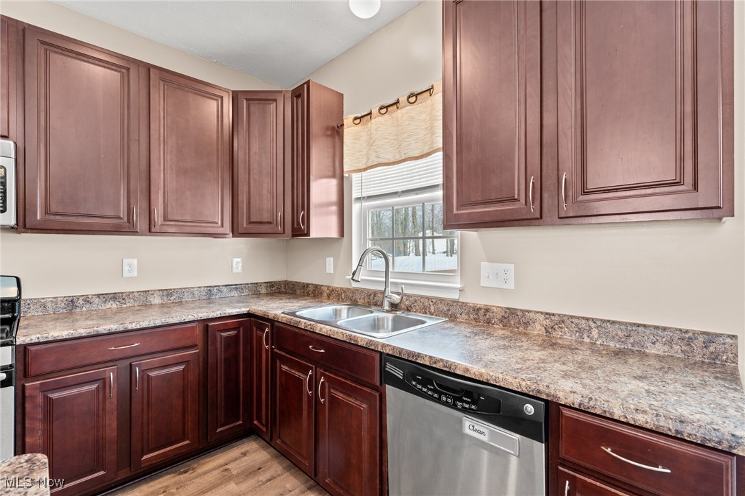 Kitchen with dark wood cabinets, mottled countertops, and a double-basin sink beneath a snowy window.