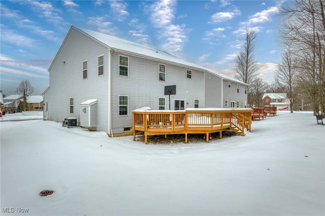 Gray-sided home with a raised wooden deck surrounded by snow.