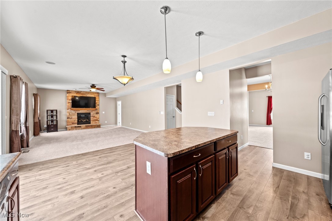 Open-plan kitchen and living room with a wood island and stone fireplace.