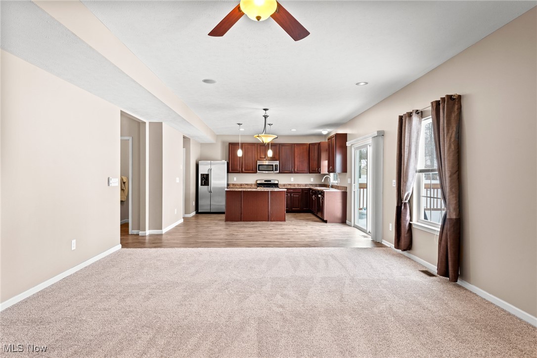 Empty living room opening to a kitchen with dark wood cabinets and a central island.
