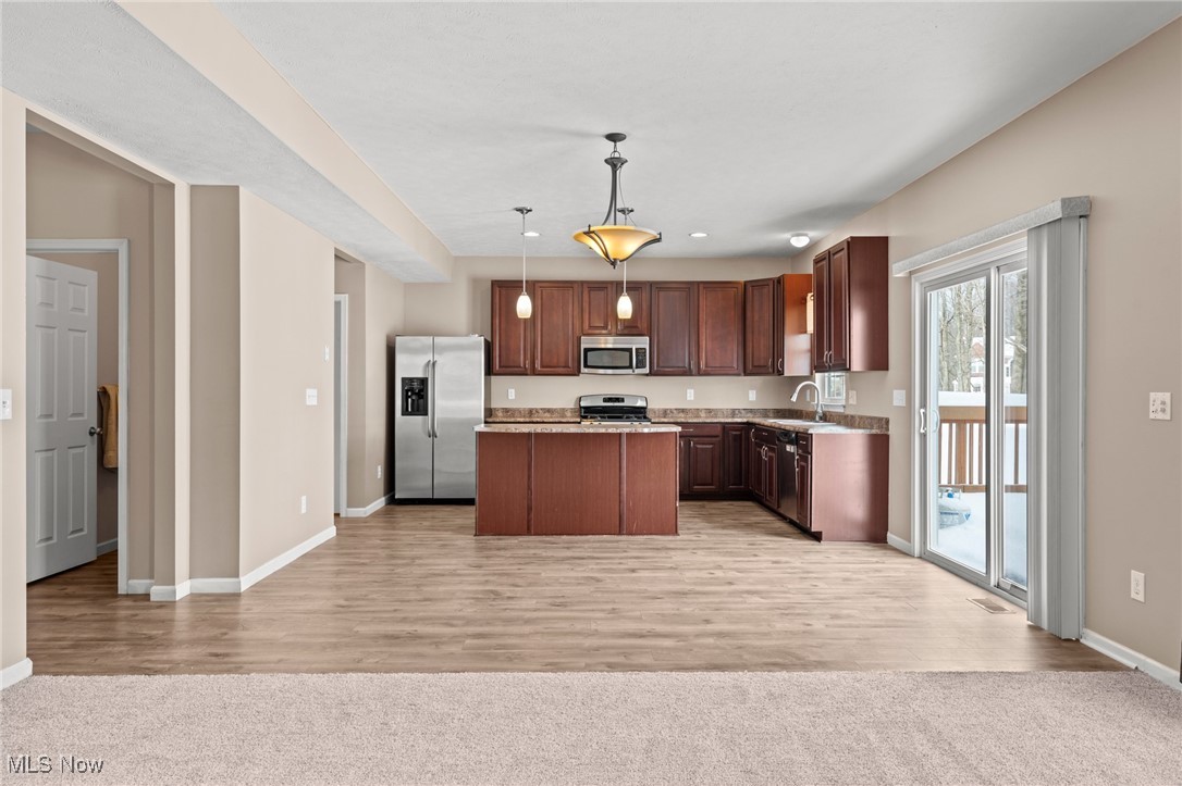Unfurnished kitchen with cherry cabinets, a central island, and sliding doors overlooking a snowy deck.