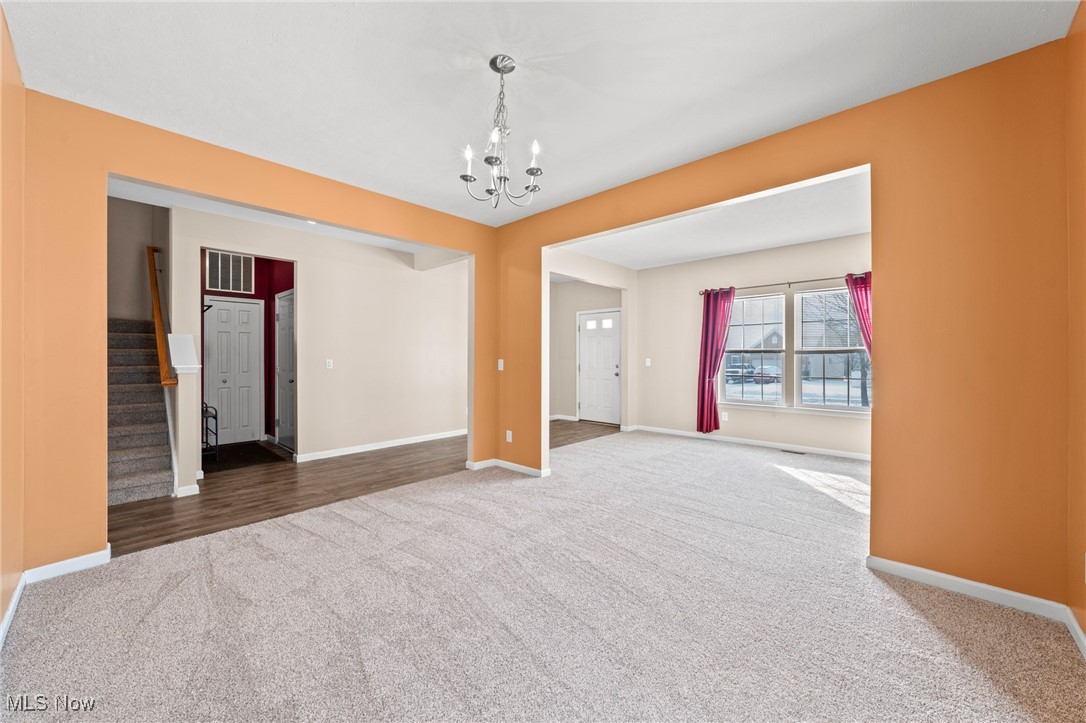 Unfurnished living area with orange walls, light carpet, and an adjoining windowed room.