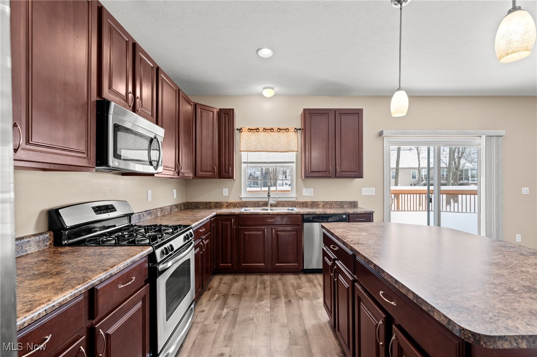 Kitchen with dark wood cabinets, a large island, stainless steel appliances, and a snowy deck view.