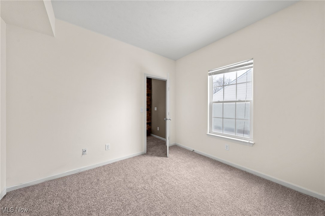 Empty carpeted room with a window and open doorway.