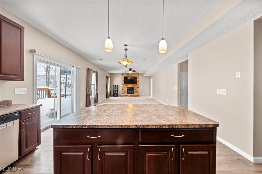 Kitchen with a large dark wood island overlooking an open living area and stone fireplace.