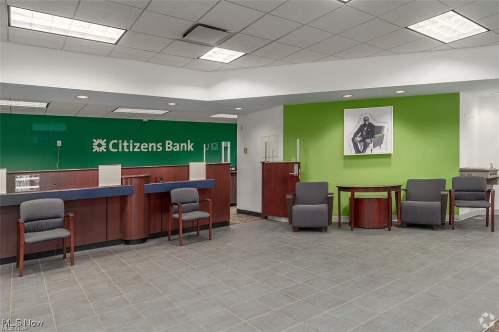 Bank lobby with Citizens Bank teller counters, gray waiting chairs, and a bright green accent wall.